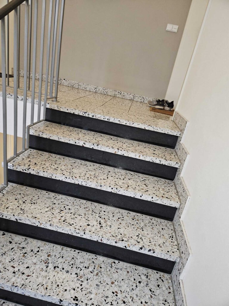 Frisch gereinigtes, glänzendes Treppenhaus aus Naturstein in einem Mehrfamilienhaus in München.
